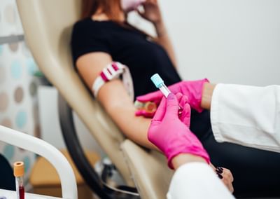 Nurse taking blood sample from a young adult woman in a medical laboratory