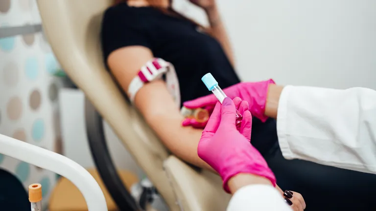 Nurse taking blood sample from a young adult woman in a medical laboratory