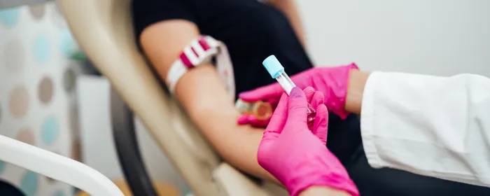Nurse taking blood sample from a young adult woman in a medical laboratory